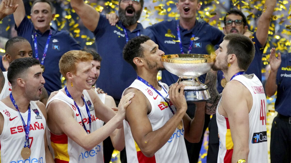 Los españoles Sebas Saiz, a la izquierda, y Juancho Hernangomez, a la derecha, besan el trofeo tras ganar la final del Eurobasket 