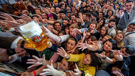 People reach out for free beer in one of the beer tents on the opening day of the 187th Oktoberfest beer festival