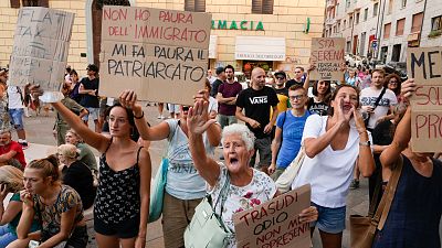 People stage a protest as Right-wing party Brothers of Italy's leader Giorgia Meloni addresses a rally as she starts her political campaign. 