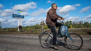 A man cycles on a road past a Ukrainian flag in the recently retaken area of Izium, Ukraine, Monday, Sept. 19, 2022