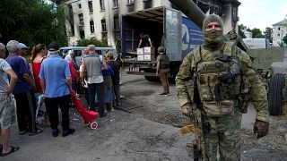 Segélyosztást felügyel a Luhanszki Népköztársaság katonája Liszicsanszkban 2022. júliusában