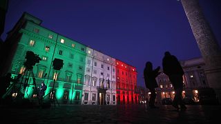Television crew stand in front of Palazzo Chigi government's headquarters, illuminated with the colours of the Italian flag, Monday, 18 January 2021.