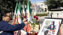 Una donna depone fiori su un altare in ricordo di Masha Amini eretto fuori dalla sede ONU di Ginevra, Svizzera, il 20 settembre 2022