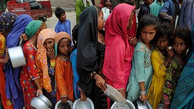 People from flood-affected areas wait to receive food distributed by the Saylani Welfare Trust, in Lal Bagh, Sindh province, Pakistan.