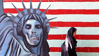 A veiled Iranian woman walks past an anti U.S painting on the wall of the former U.S Embassy in Tehran, Saturday, July 2, 2005. 