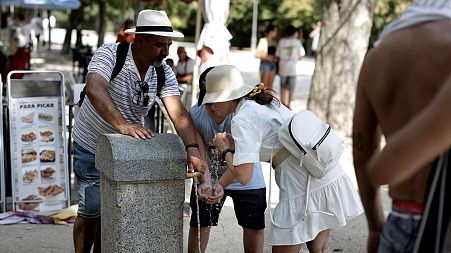 People cool off at a public fountain in a park in central Madrid during a heatwave, on August 2, 2022.