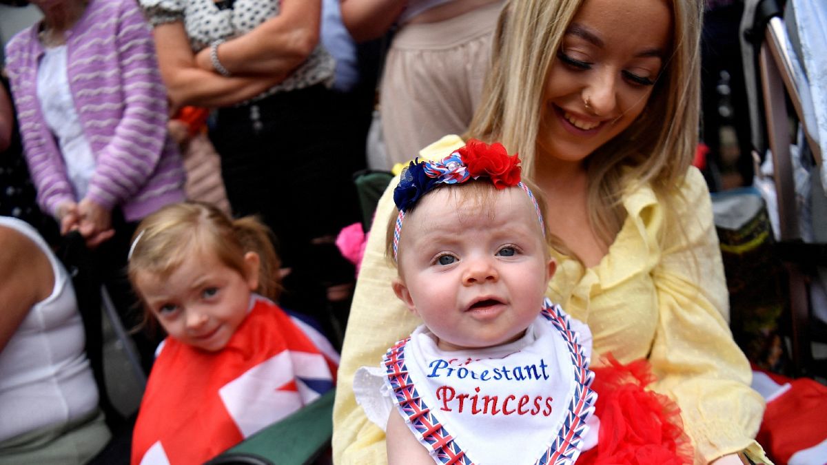 A woman and her baby watch the Twelfth of July Orange Order celebrations in the city centre of Belfast, Northern Ireland July 12, 2022