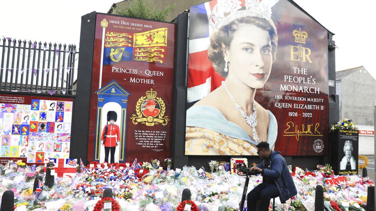 Um homem olha para as flores depositadas em tributo à Rainha Isabel II, na Shankill Road, em Belfast, na Irlanda do Norte