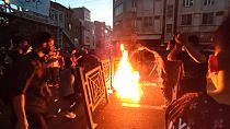 Manifestantes incendian y bloquean la calle durante una protesta por la muerte de una mujer que fue detenida por la policía de la moralidad