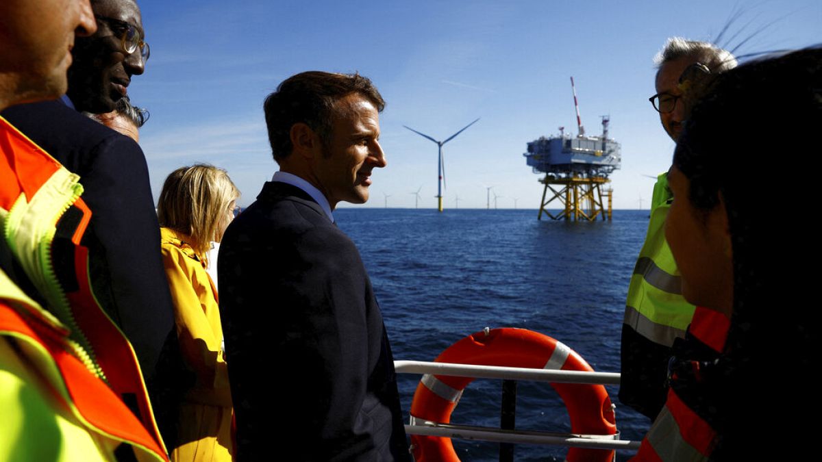 Le président français Emmanuel Macron discute avec des travailleurs à bord d'un bateau lors d'une visite au parc éolien offshore de Saint-Nazaire, 22/09/22