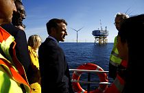Le président français Emmanuel Macron discute avec des travailleurs à bord d'un bateau lors d'une visite au parc éolien offshore de Saint-Nazaire, 22/09/22