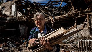 A woman collects wood for heating from a destroyed school where Russian forces were based in the recently retaken area of Izium, Ukraine, Monday, Sept. 19, 2022.