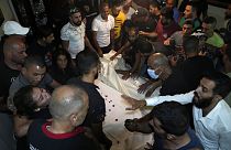 Los dolientes se reúnen en torno a dos de las varias víctimas en Trípoli, norte del Líbano, el 23 de septiembre de 2022.