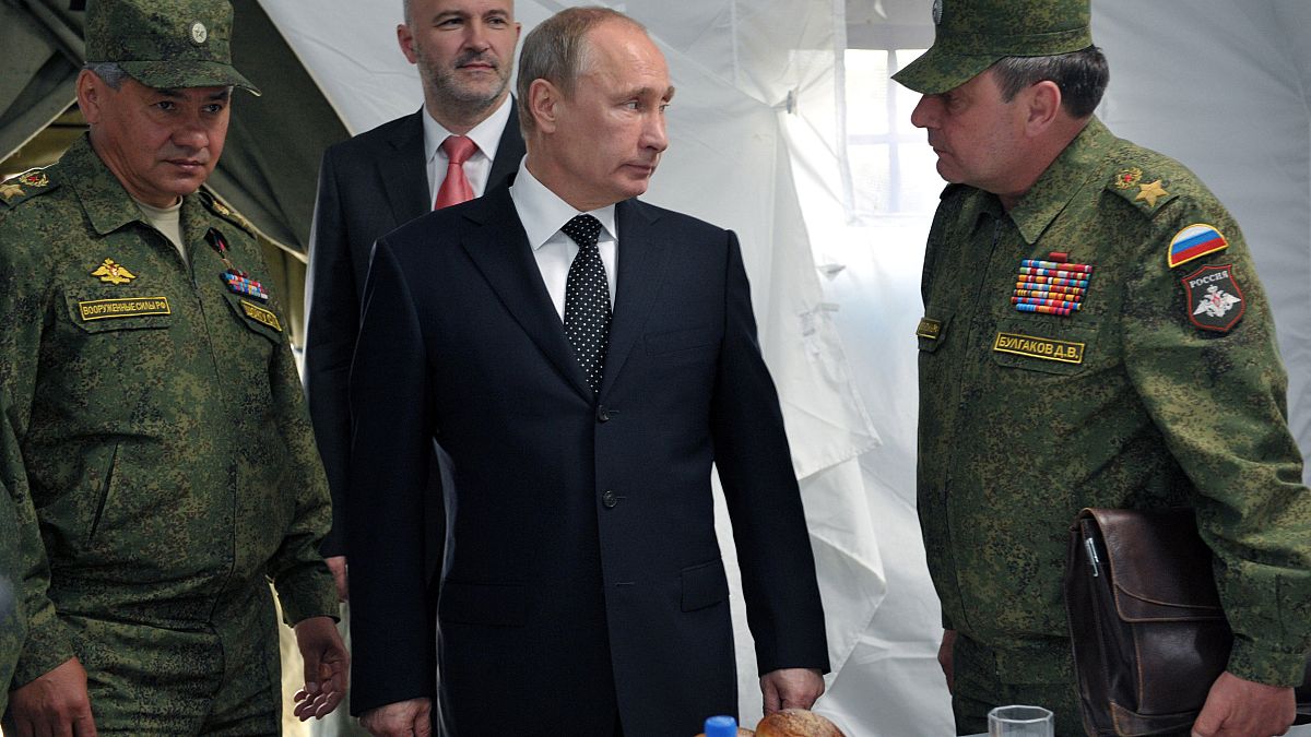 بوتين مستمعاً إلى نائب وزير الدفاع سابقاً دمتري بولغاكوف (يمين) ويظهر وزير الدفاع سيرغي شويغو إلى يسار الصورة
