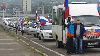 Two men pose for a photo in front of motorcade organised to support voting in a referendum in Luhansk, 23 September 2022