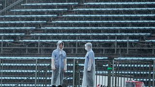 متطوعون وسط مدرجات خالية حيث أوقفت الأمطار الغزيرة تصفيات موتو 2 المؤهلة لسباق الجائزة الكبرى للدراجات النارية اليابانية في موتيجي، شمال طوكيو، 24 سبتمبر 2022