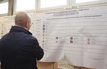 Ein Mann in Bologna betrachtet die Übersicht der antretenden Parteien