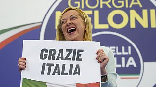 زعيمة حزب اليمين المتطرف، جيورجيا ميلوني، تحمل لافتة مكتوب عليها "شكرا لك إيطاليا" في المقر الانتخابي لحزبها في روما، الأحد 25 سبتمبر 2022. 