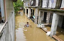 Κάτοικος περπατάει σε πλημμυρισμένο δρόμο στις Φιλιππίνες με το νερό να φτάνει μέχρι το στήθος του