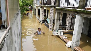 Κάτοικος περπατάει σε πλημμυρισμένο δρόμο στις Φιλιππίνες με το νερό να φτάνει μέχρι το στήθος του