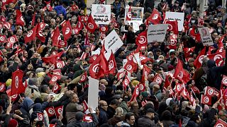 متظاهرون تونسيون يرفعون لافتات وأعلام وطنية، في العاصمة تونس، 20 مارس 2022.