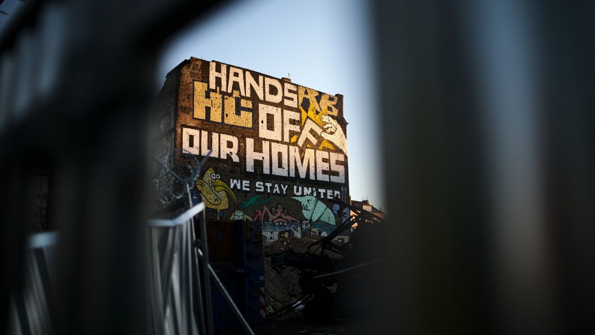 Graffiti with the slogan "Hands off our homes" is displayed at the building wall of an alternative housing project in Berlin, Germany, Thursday, Jan. 6, 2022