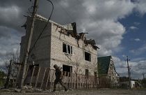A Ukrainian serviceman from Dnipro-1 regiment walks past a damaged building in the retaken village of Shchurove.