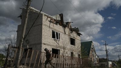 A Ukrainian serviceman from Dnipro-1 regiment walks past a damaged building in the retaken village of Shchurove.