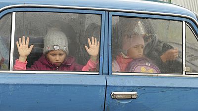 Los niños miran a través de las ventanillas mientras ellos y otros refugiados de Járkov en Ucrania llegan al campamento en Belgorod, Rusia, el 14 de septiembre de 2022.