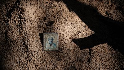Icône sur le sol entre des tombes vides après l'exhumation de corps dans une fosse commune découverte à Izyum en Ukraine après l'invasion russe - 25.09.2022