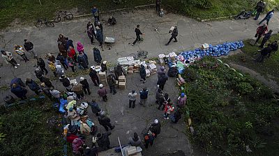 Люди ждут получени�� гуманитарной помощи на пункте раздачи в недавно взятом городе Изюм, Украина, воскресенье, 25 сентября 2022 года