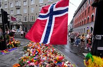 A Norwegian national flag flutters over flowers and rainbow flags near the London Pub in Oslo.