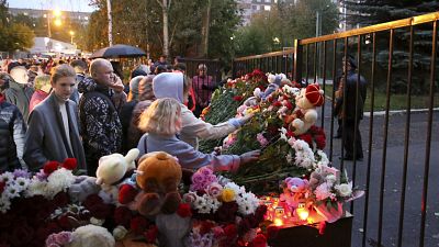 Famílias das vítimas deixam flores no portão da escola.
