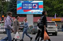People walk past a billboard reading 'Forever with Russia' in Luhansk, eastern Ukraine, Tuesday, Sept. 27, 2022