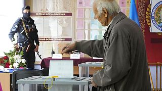Un hombre acude a votar frente a un hombre armado en un colegio electoral.