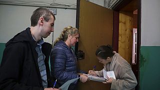 Nő szavaz a donyecki "népszavazáson" a választási biztosok viszla tekintete előtt