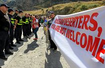 Georgian police form a line in front of activists holding an anti-Russian banner during an action organized by political party Droa near the border crossing at Verkhny Lars