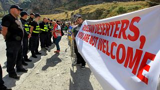 Georgian police form a line in front of activists holding an anti-Russian banner during an action organized by political party Droa near the border crossing at Verkhny Lars