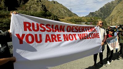 Акция протеста на границе с Россией. Плакат с надписью "Российские дезертиры, вам здесь не рады"