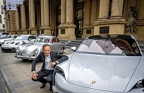 Le PDG du constructeur automobile Porsche, Oliver Blume, s'agenouille à côté de voitures Porsche au début de la cotation de Porsche à la bourse de Francfort