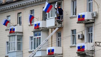 Munkások tesznek ki orosz zászlókat egy épületre  Luhanszkban 2022. szeptember 27-én
