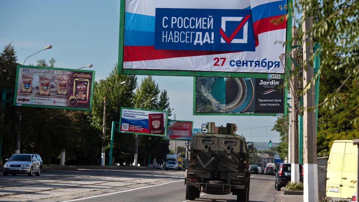 A military vehicle drives along a street with a billboard that reads: "With Russia forever, September 27", prior to a referendum in Luhansk, Ukraine on Sept. 22, 2022
