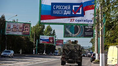 A military vehicle drives along a street with a billboard that reads: "With Russia forever, September 27", prior to a referendum in Luhansk, Ukraine on Sept. 22, 2022