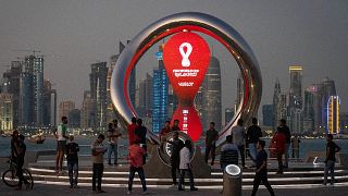 People gather around the official countdown clock showing remaining time until the kick-off of the World Cup 2022, in Doha