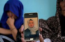 Mulher mostra a foto de uma jovem de 19 anos morta no atentado