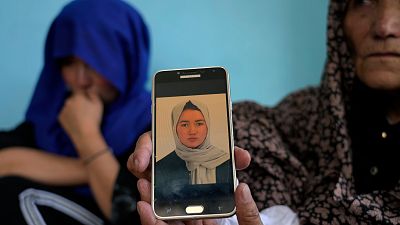 Mulher mostra a foto de uma jovem de 19 anos morta no atentado
