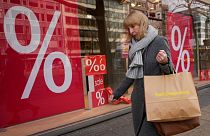 A woman walks with purchases past a store in Berlin, April 1, 2022. 