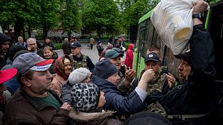 A Police officer, right, distributes humanitarian aid to local residents in Lyman, Donetsk region, eastern Ukraine, Saturday, April 30, 2022. 