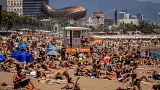 People sunbathe on the beach in Barcelona, Spain.