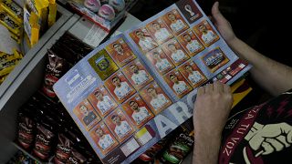 Un vendedor muestra su álbum con los cromos de la selección argentina.